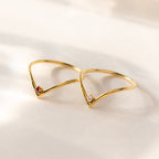 Two delicate Chevron Birthstone Rings with V-shaped gold bands, each set with a small gemstone, create a subtle and elegant birthstone jewelry look on a light background.