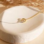 Elegant Interlocking Circles Bracelet in two-tone silver and gold—perfect for minimalist style or as a thoughtful anniversary gift, beautifully displayed on a white ceramic dish.
