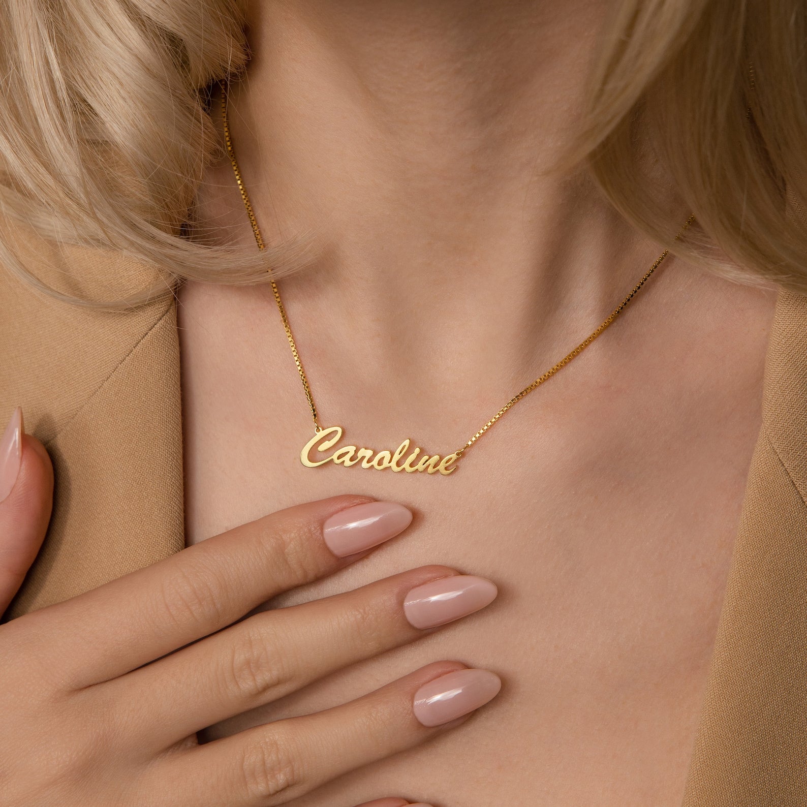 A woman wearing the Natural Name Necklace in Box Chain with "Caroline" gently touches it—a thoughtful, cherished gift.