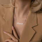 Woman in a beige blazer touches her collar while wearing the Natural Name Necklace in Box Chain—a minimalist custom piece, perfect as a thoughtful gift.
