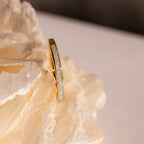 The White Opal Inlay Band in 18K Gold features an iridescent opal inlay and is shown resting on a large, textured crystal rock.