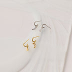 Opal Moon Mini Hoops—crescent-shaped huggie earrings in gold and silver, shown on a white textured surface—are perfect for creating a stunning earring stack.