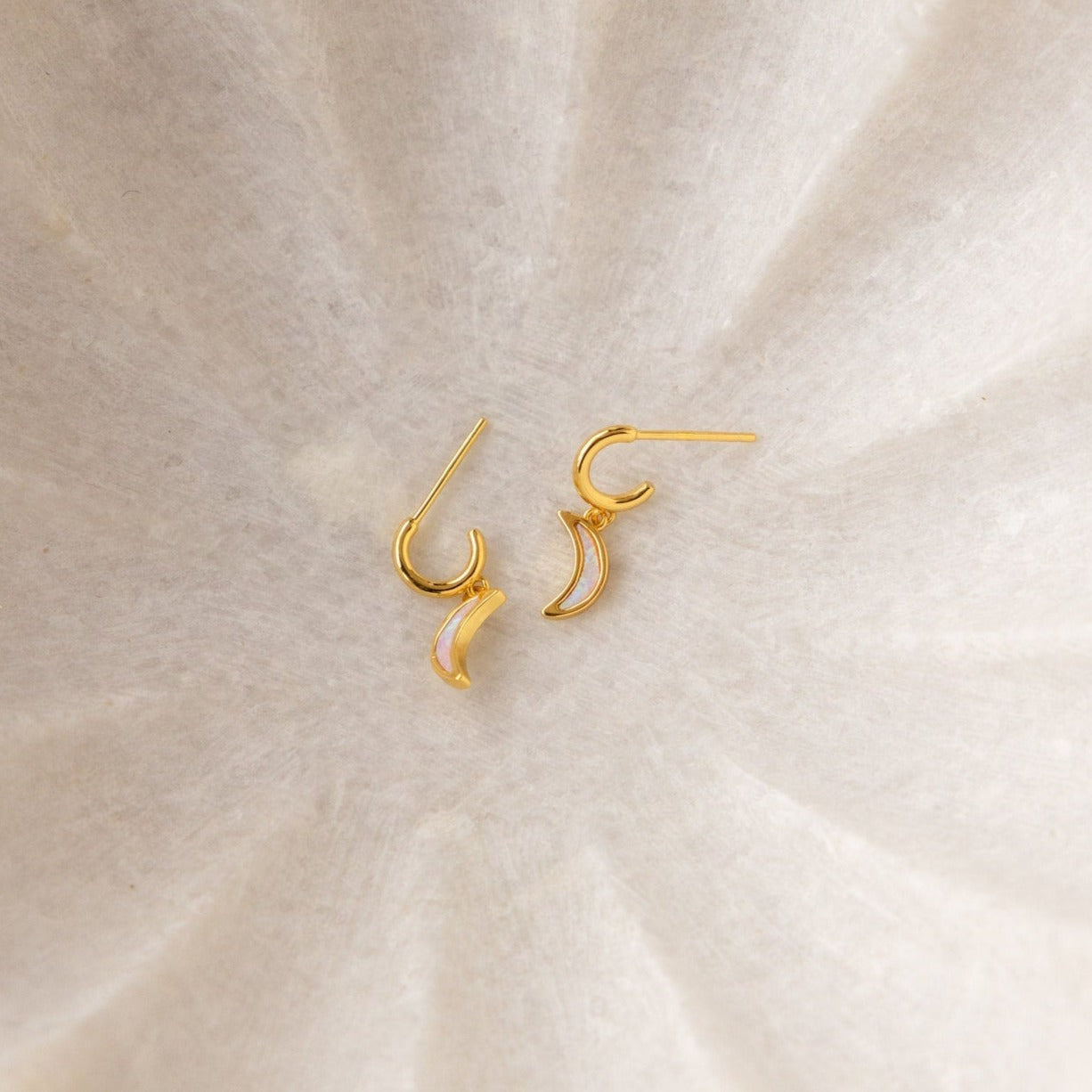 Opal Moon Mini Hoops, gold crescent-shaped earrings shown on a light textured surface—perfect for adding a touch of elegance to your earring stack.