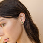 A close-up of a woman’s ear wearing elegant Triple Birthstone Studs—a meaningful gift for mothers and daughters.