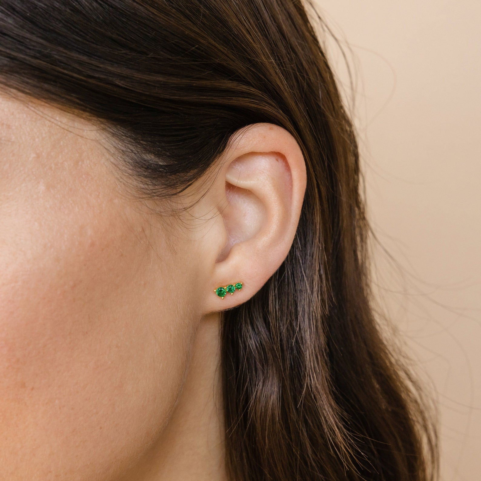 Close-up of a woman's ear wearing Triple Birthstone Studs—three small green bars arranged vertically. These stylish earrings make a perfect, thoughtful gift for mothers and daughters.