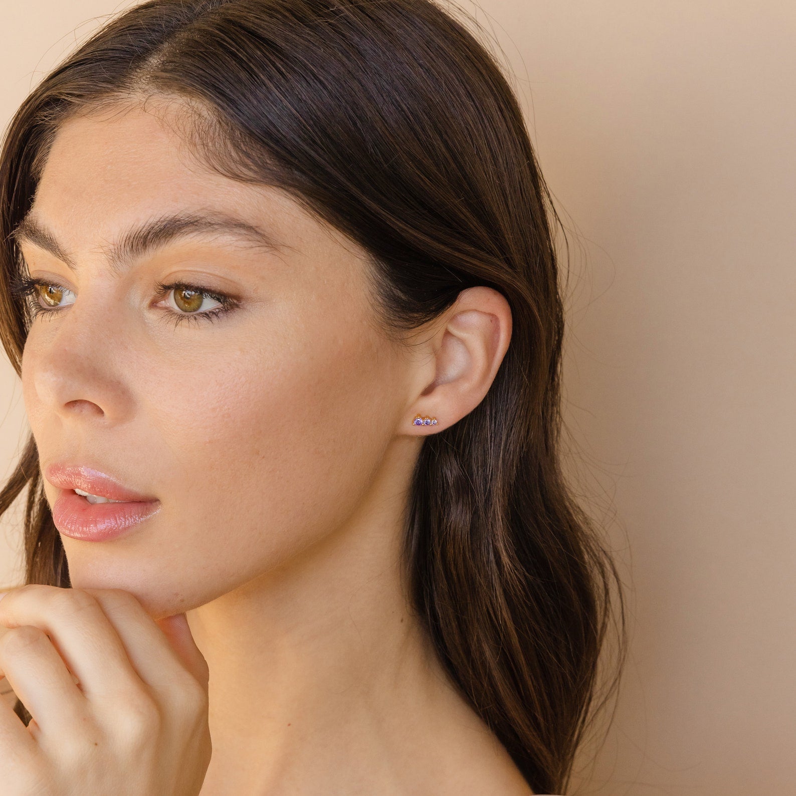 Woman with long brown hair wears small Triple Birthstone Studs with a zigzag design, looking to the left—an elegant gift for mothers and daughters.