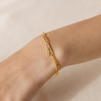 The Large Letter Bracelet with a gold "A" charm adorns the wrist against a neutral backdrop—a chic, personalized accessory for everyday wear.