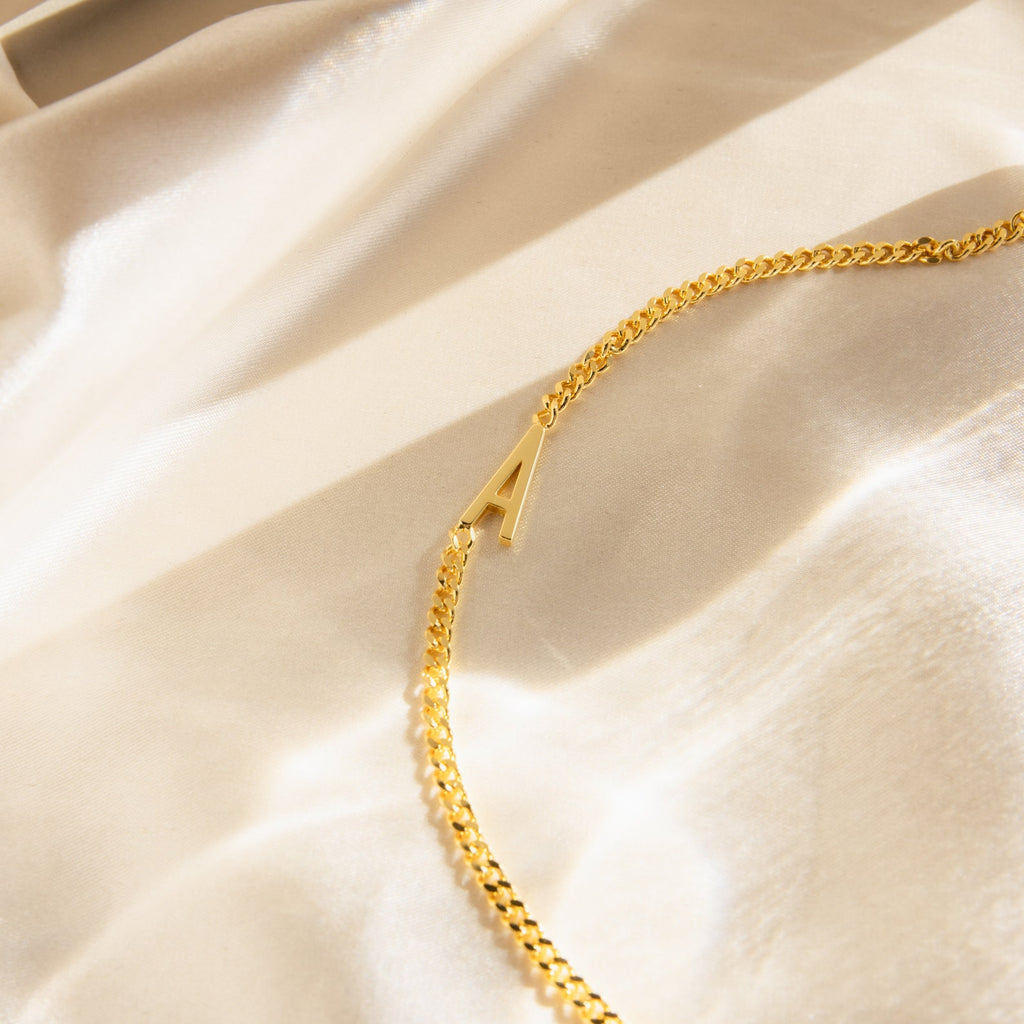 Large Letter Bracelet on beige satin fabric, accented by soft sunlight and shadows—ideal for everyday wear or paired with a personalized gold necklace for a thoughtful, stylish touch.