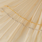 The Singapore Twist Bracelet, featuring a gold and silver twisted rope design, is displayed on a cream-colored pleated fabric background.