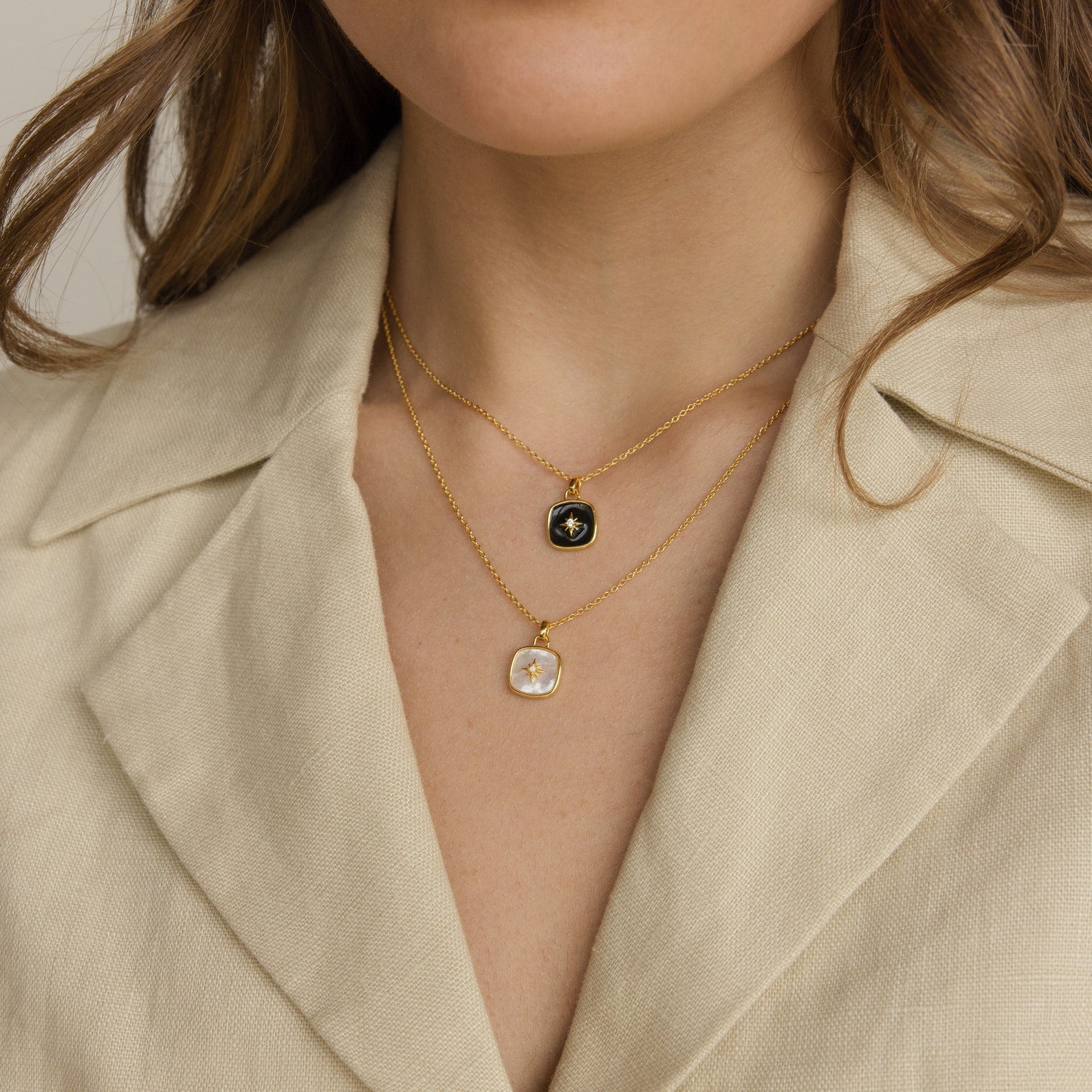 Woman wearing a beige blazer and two gold necklaces, including a striking Hermoine Pendant Necklace with square black and white pendants.