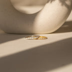 The Crescent Opal Ring, available in both silver and gold and accented with delicate opals, rests on a sunlit surface. Ideal as an anniversary gift or a meaningful promise ring to celebrate cherished moments.