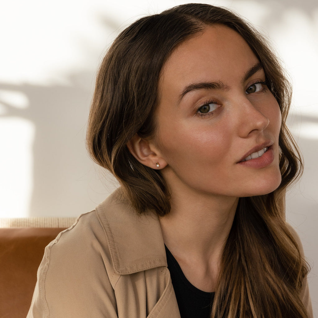 A woman with long hair and a tan jacket, wearing elegant Raindrop Pearl Onyx Studs.