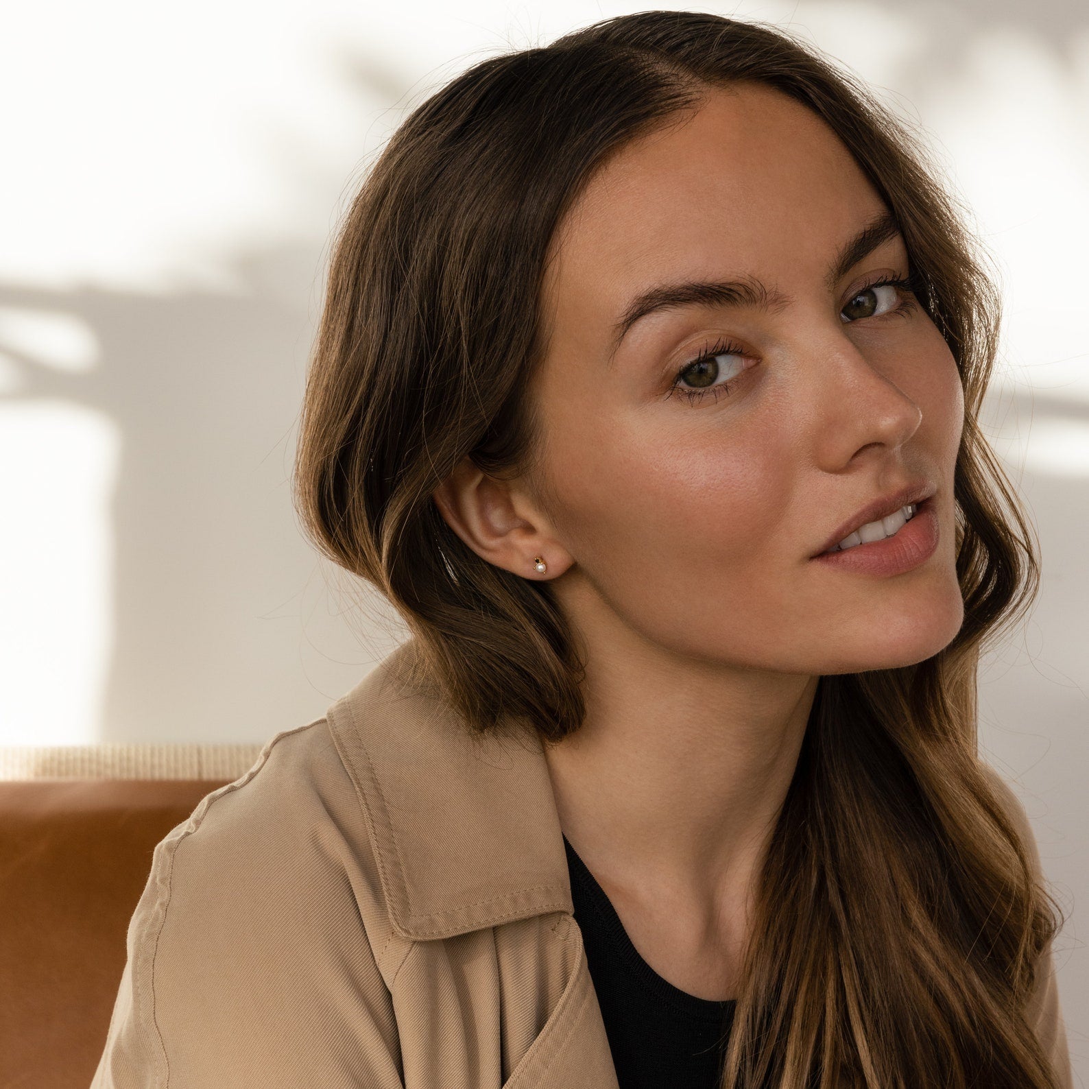 A woman with long hair and a tan jacket, wearing elegant Raindrop Pearl Onyx Studs.