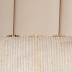 The Triple Birthstone Studs—blue, green, and pearl pairs—are displayed on a textured beige surface, making them a thoughtful gift for mothers, daughters, or anyone who loves elegant birthstone earrings.