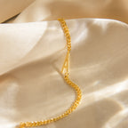 Large Letter Bracelet with a gold curb chain and A charm, displayed on soft beige satin—a stylish, personalized accessory for everyday wear.