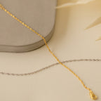 Gold and silver twisted chain necklaces on a cream surface with a neutral background pair perfectly with the minimalist Singapore Twist Bracelet, creating an elegant, layered look.