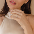 A woman in a satin top shows off the Layla Opal Diamond Ring—an elegant, minimal design with diamonds—on her hand, lips slightly parted.