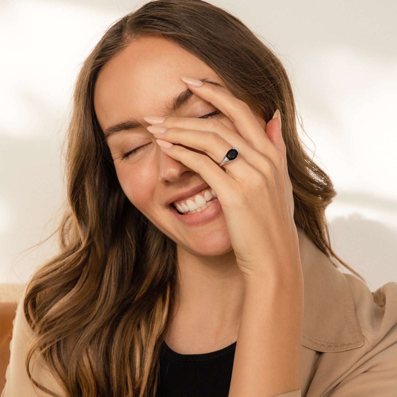 Woman smiles with eyes closed, covering part of her face with her hand while wearing the Dusk Signet Ring—a bold piece that adds a touch of elegance to her look.