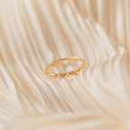 The Delicate Pearl Diamond Ring, adorned with small diamonds, is displayed on soft, cream-colored fabric with gentle folds.