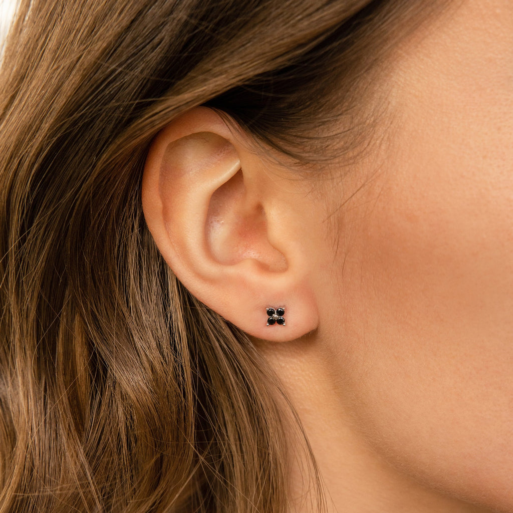 Close-up of a woman's ear wearing Black Flower Studs—small black earrings inspired by vintage and Art Deco jewelry.