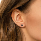 Close-up of a woman's ear wearing Black Flower Studs—small black earrings inspired by vintage and Art Deco jewelry.