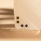 Three pairs of small stud earrings with black stones, including the elegant Black Flower Studs and vintage Art Deco-inspired designs, are displayed on textured white fabric.