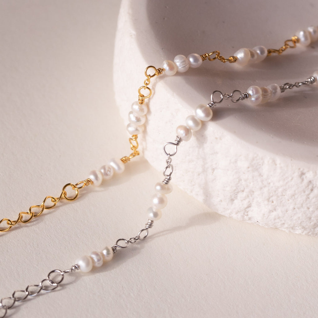 The Hali Pearl Station Bracelet rests on a textured white surface—a timeless choice for bridal jewelry or the perfect bridesmaid gift.