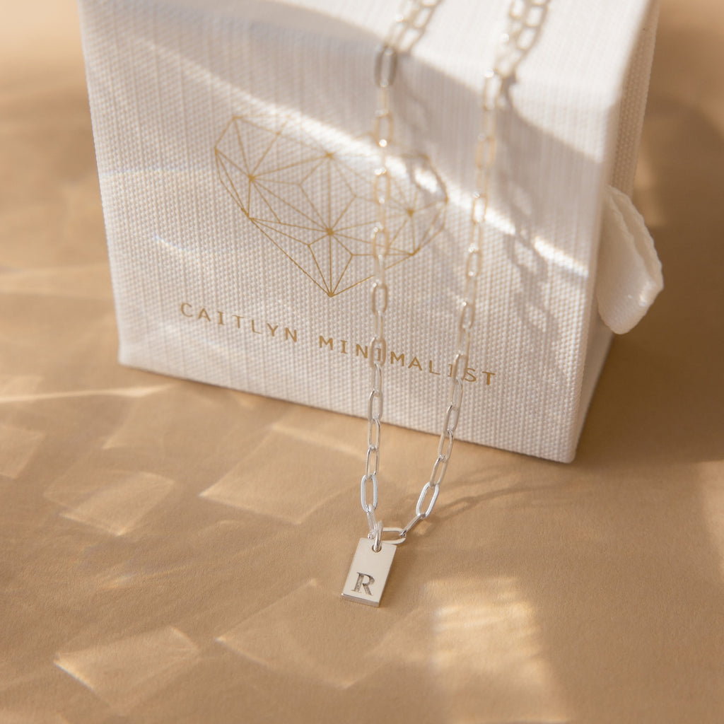The Mini Initial Paperclip Necklace showcases your chosen initial pendant on a sleek chain, offering a subtle personalized touch to any look.