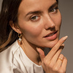 A woman rests her hand on her chin, elegantly displaying the Pearl Drop Earrings Set.