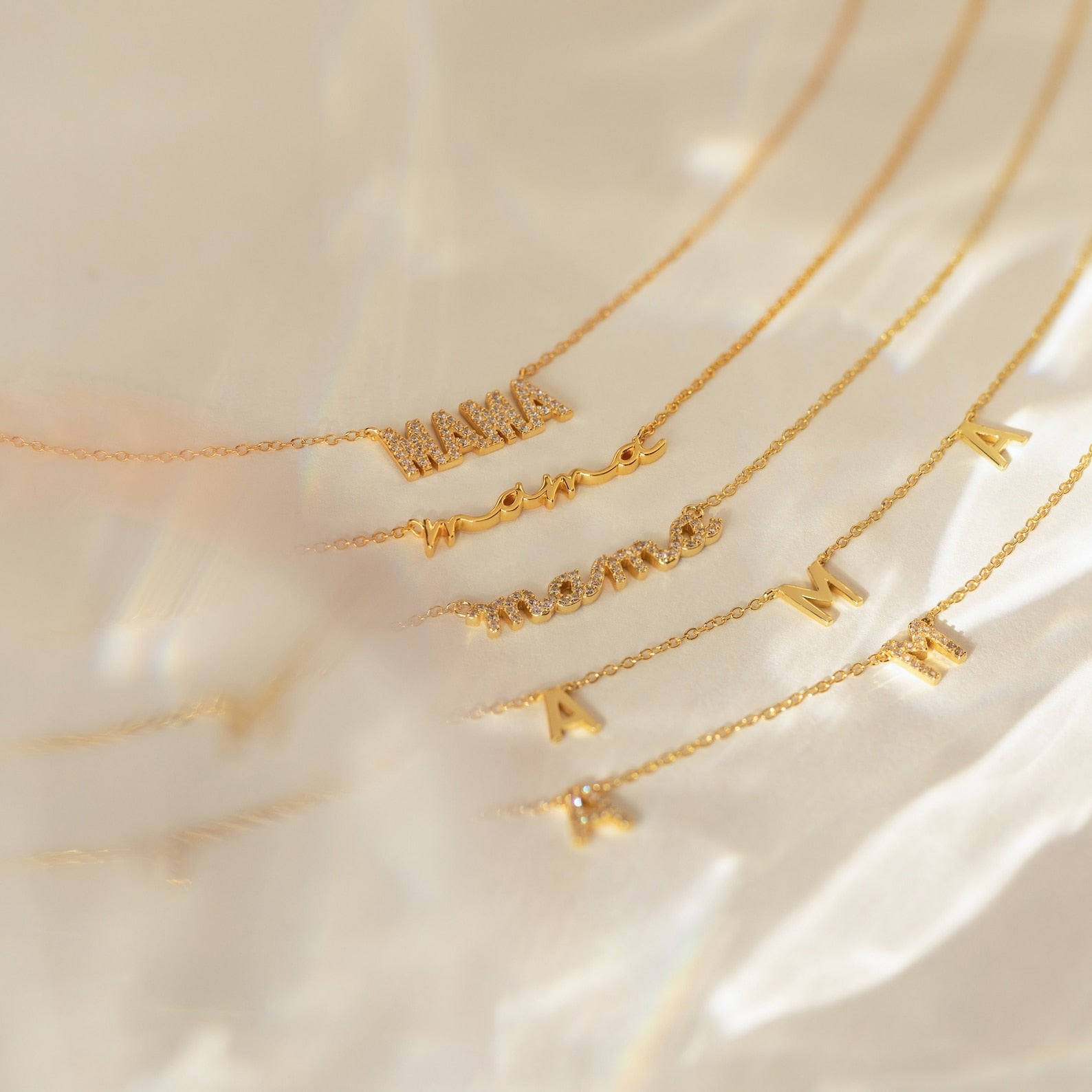 Mama Necklaces, crafted in 925 sterling silver with letter charms and word pendants, are displayed on a softly blurred background—making them a thoughtful gift for mom.
