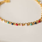 Rainbow Station Bracelet features a gold double chain decorated with small, colorful beads in pink, blue, white, red, and turquoise against a light background.