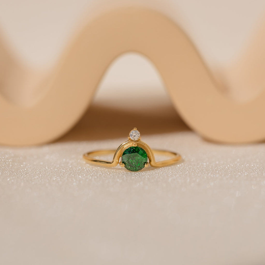 The Duo Vintage Birthstone Ring features a gold band with a round green gemstone and a small diamond, elegantly displayed—a personalized mom ring, ideal for Mother's Day or as a special gift for new moms.
