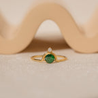 The Duo Vintage Birthstone Ring features a gold band with a round green gemstone and a small diamond, elegantly displayed—a personalized mom ring, ideal for Mother's Day or as a special gift for new moms.