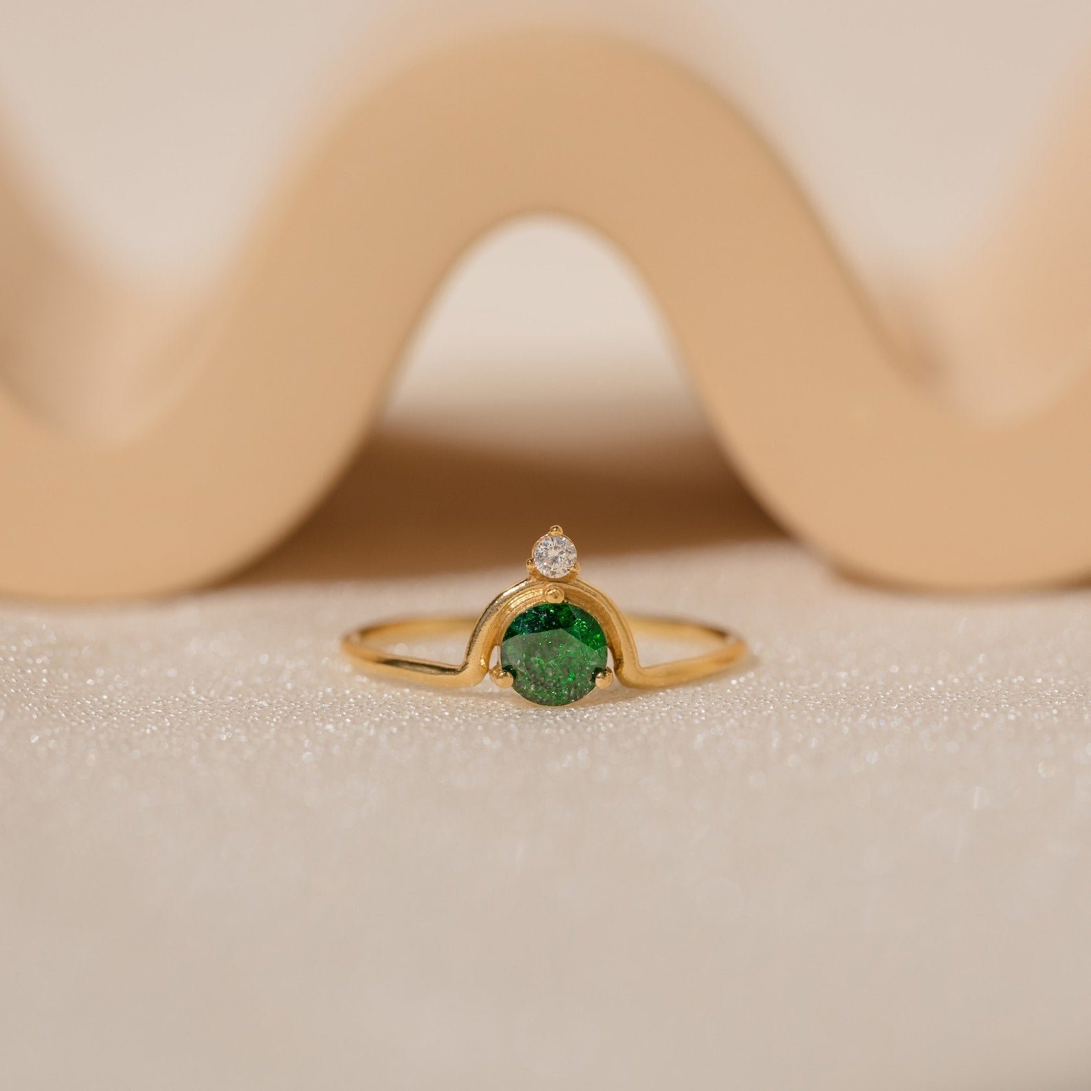 The Duo Vintage Birthstone Ring features a gold band with a round green gemstone and a small diamond, elegantly displayed—a personalized mom ring, ideal for Mother's Day or as a special gift for new moms.