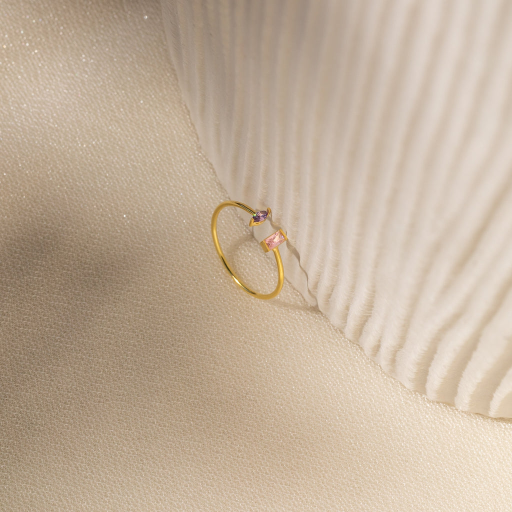 The Duo Marquise Baguette Ring gleams atop a textured cream fabric, highlighting the elegance and craftsmanship of this handmade jewelry piece.