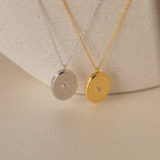 Two round pendant necklaces, one silver and one gold with a central gemstone, make a sentimental gift—perfect for pairing with the Eliza Oval Locket Necklace or a treasured photo locket. Display on a soft surface for added elegance.