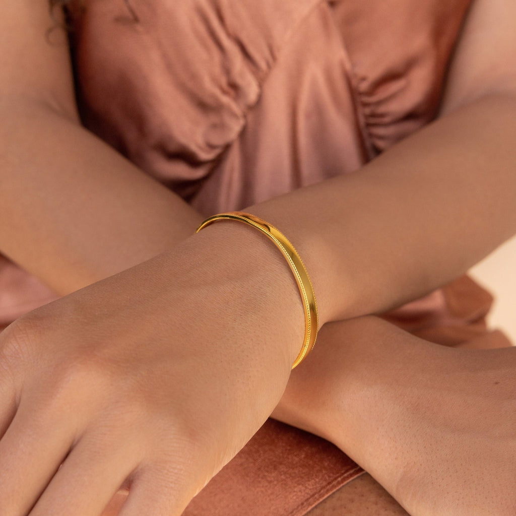 A person wearing the Alyssa Cuff Bracelet, styled with a silky rose-colored top.