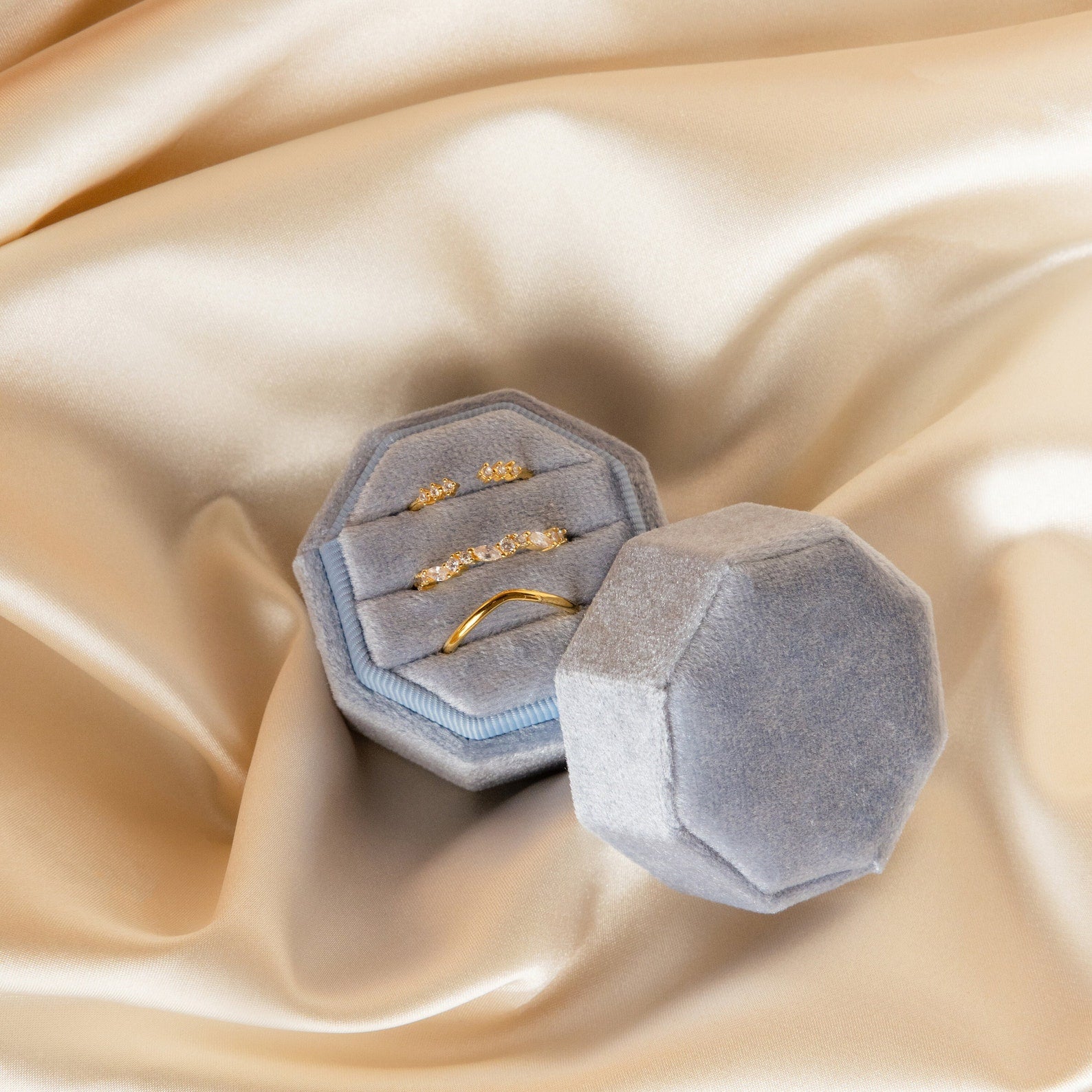 The Mystery Ring Box showcases four gold rings on soft champagne-colored satin, making it a stylish addition to your collection or a convenient ring sizer for your favorite styles.