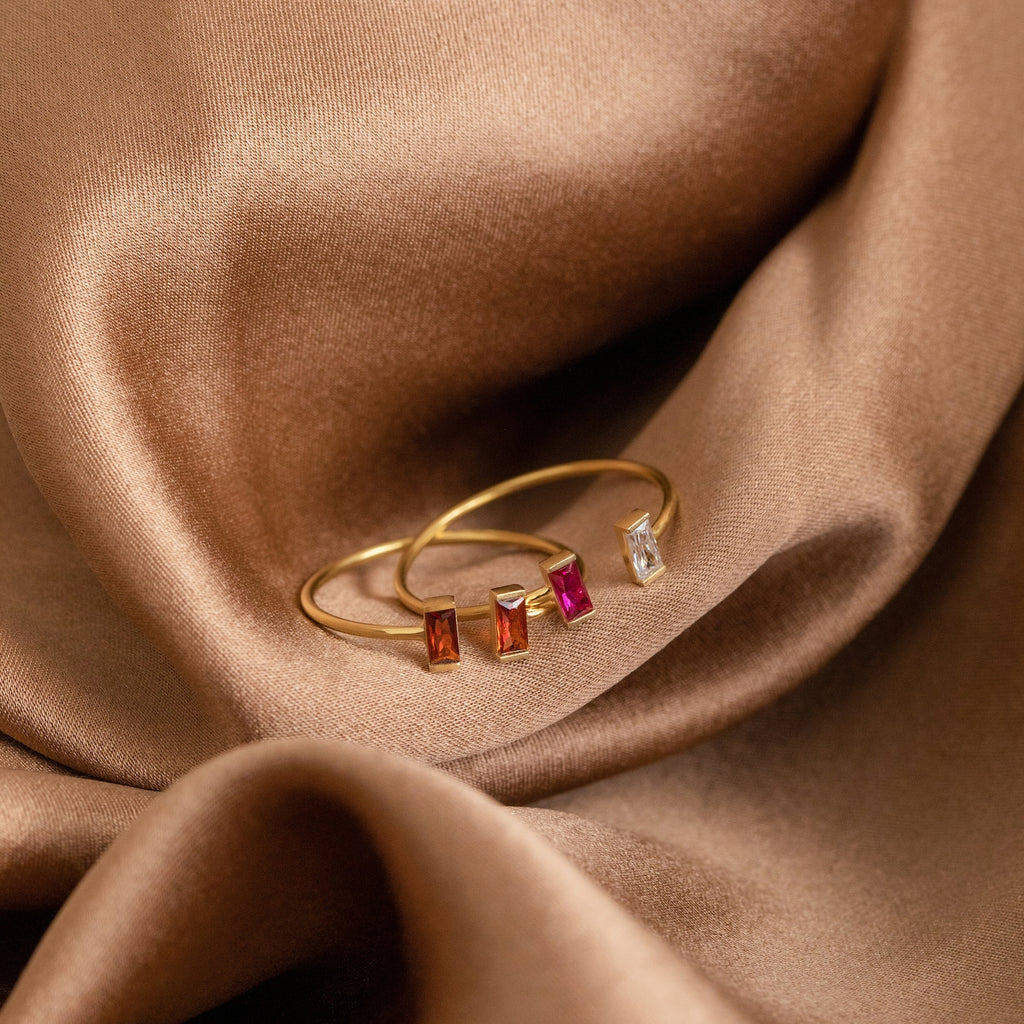 The Duo Vertical Baguette Ring features two baguette-cut rectangular red and white gemstones set on brown satin—a sophisticated option for a personalized gift or custom birthstone ring.