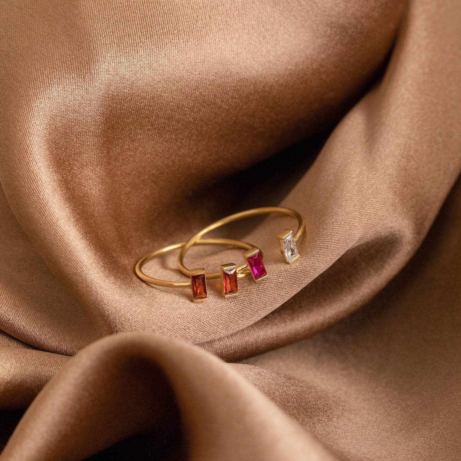 The Duo Vertical Baguette Ring features two baguette-cut rectangular red and white gemstones set on brown satin—a sophisticated option for a personalized gift or custom birthstone ring.