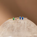 The Duo Vertical Baguette Ring features two elegant rectangular gemstones set vertically—an ideal choice for a personalized gift or custom birthstone ring, beautifully displayed on a translucent, textured surface.