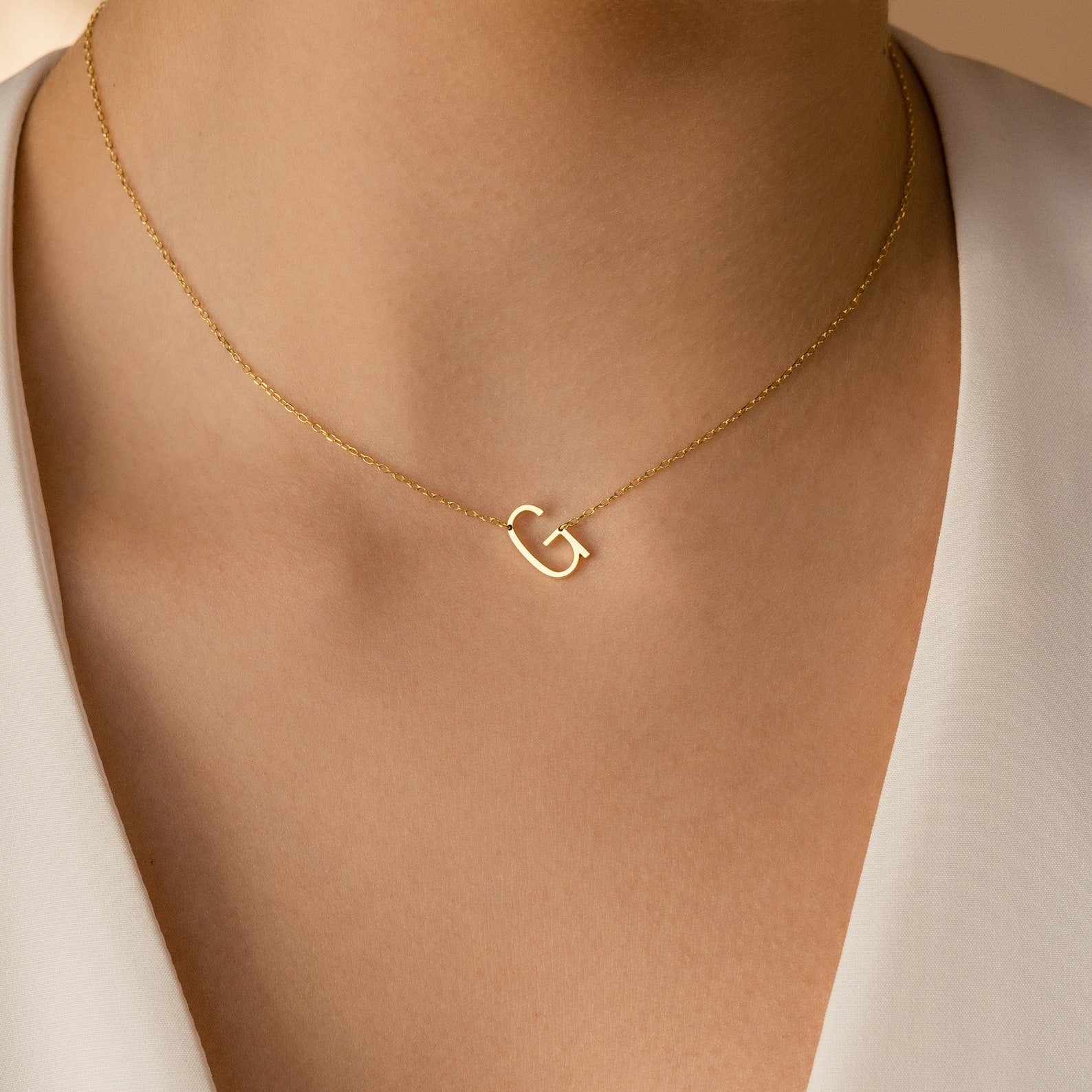 The Mini Sideways Initial Necklace features a gold sideways "G" pendant, offering an elegant and personalized touch—an ideal gift for someone special.