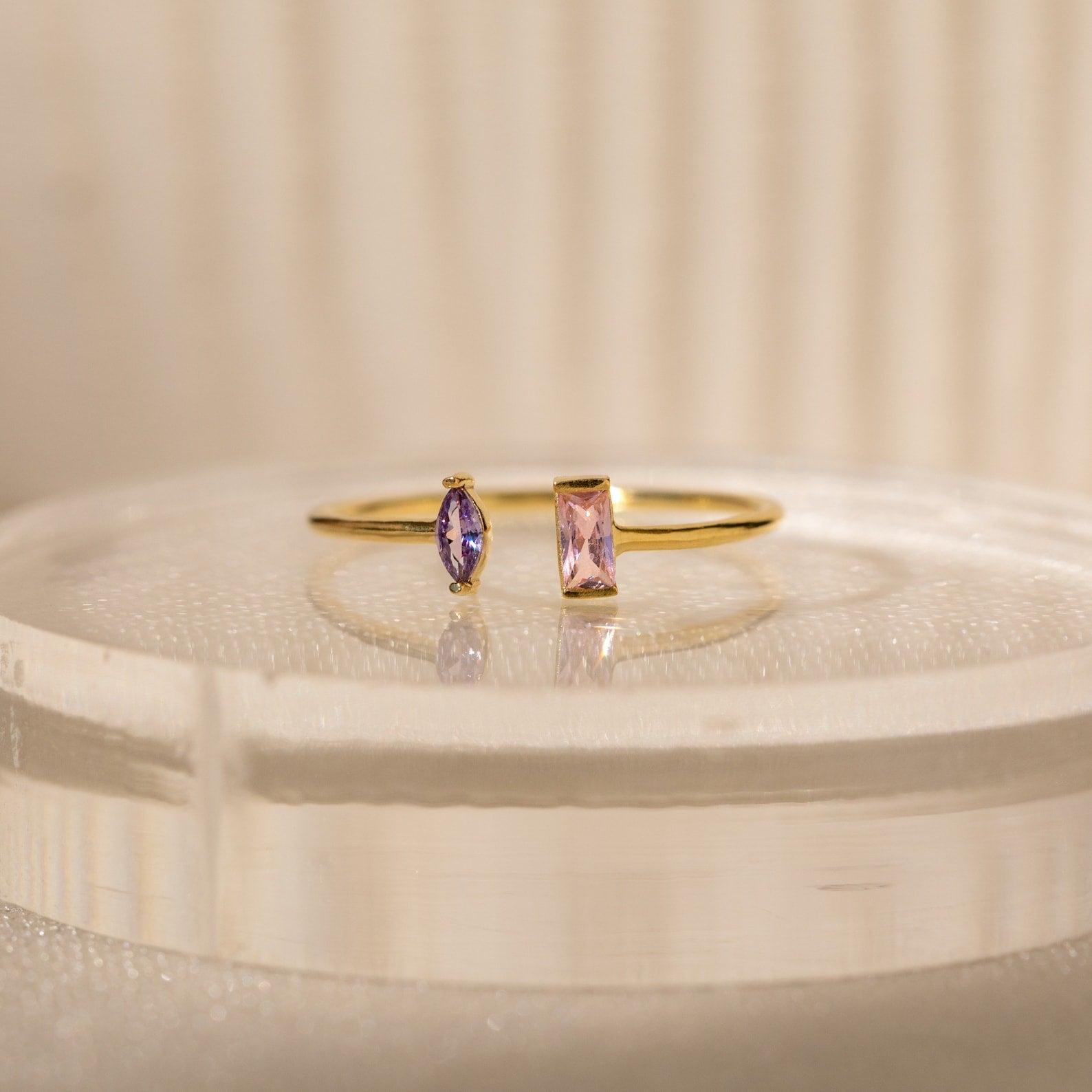 The Duo Marquise Baguette Ring showcases a purple marquise and a pink baguette stone on a translucent band. Experience the allure of handcrafted jewelry with this personalized gemstone ring.