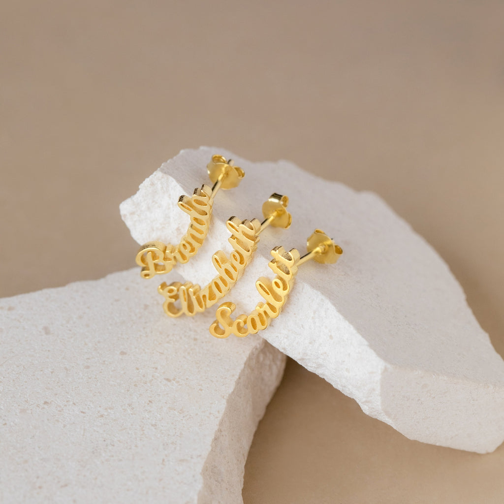 The Mellow Name Earrings, shown on a white stone, make a perfect personalized gift for someone special.
