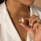 A person in a white shirt holds open the Eliza Oval Locket Necklace, revealing it as a cherished sentimental gift worn close to their neck.