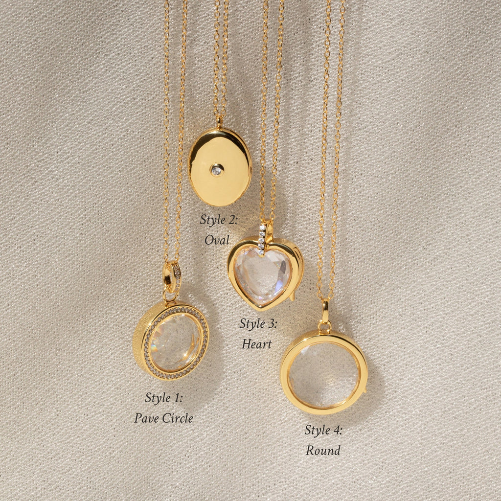 Four gold Crystal Locket Necklaces rest on fabric, each with a unique pendant shape: circle, oval, heart, and round. One locket is perfect for keeping special memories close.