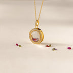 Crystal Locket Necklaces feature a gold pendant with a large faceted gemstone, surrounded by small gems, offering timeless elegance and beautifully displayed on a light surface.