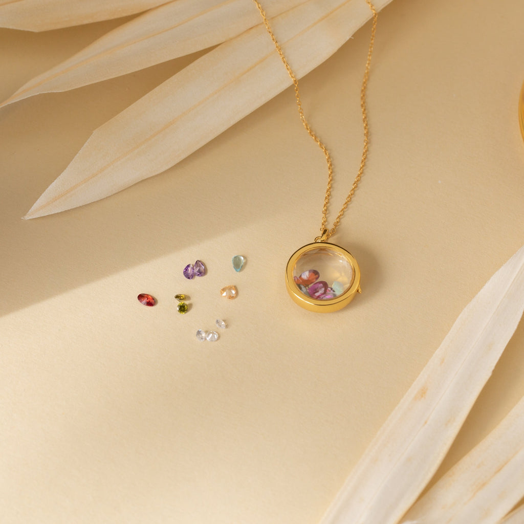 Crystal Locket Necklaces feature a gold chain with a round glass pendant and colorful gemstones, creating a beautiful keepsake accessory to hold cherished memories.