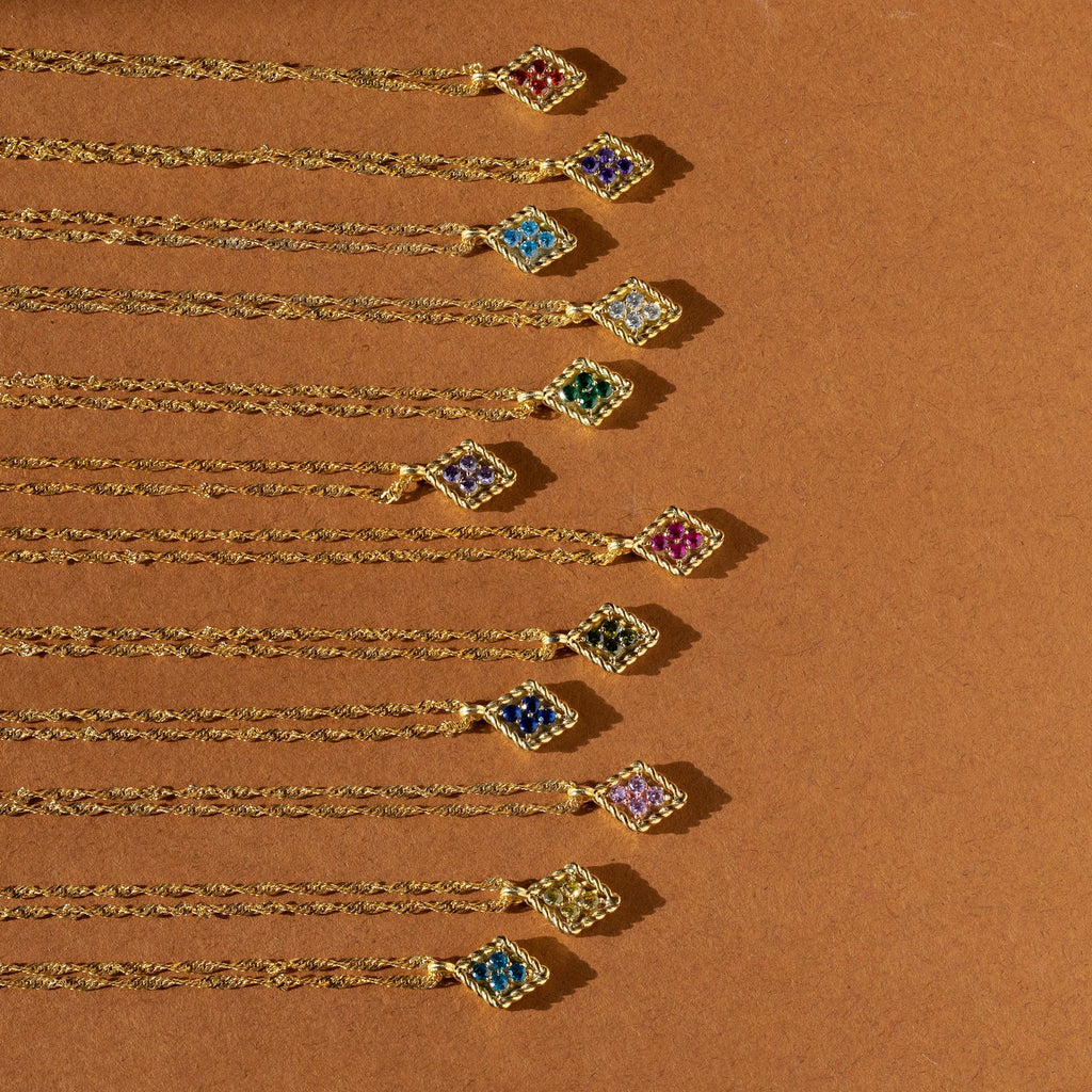 Ten Birthstone Diamond Pendant Necklaces are arranged in a neat diagonal line on a brown background.