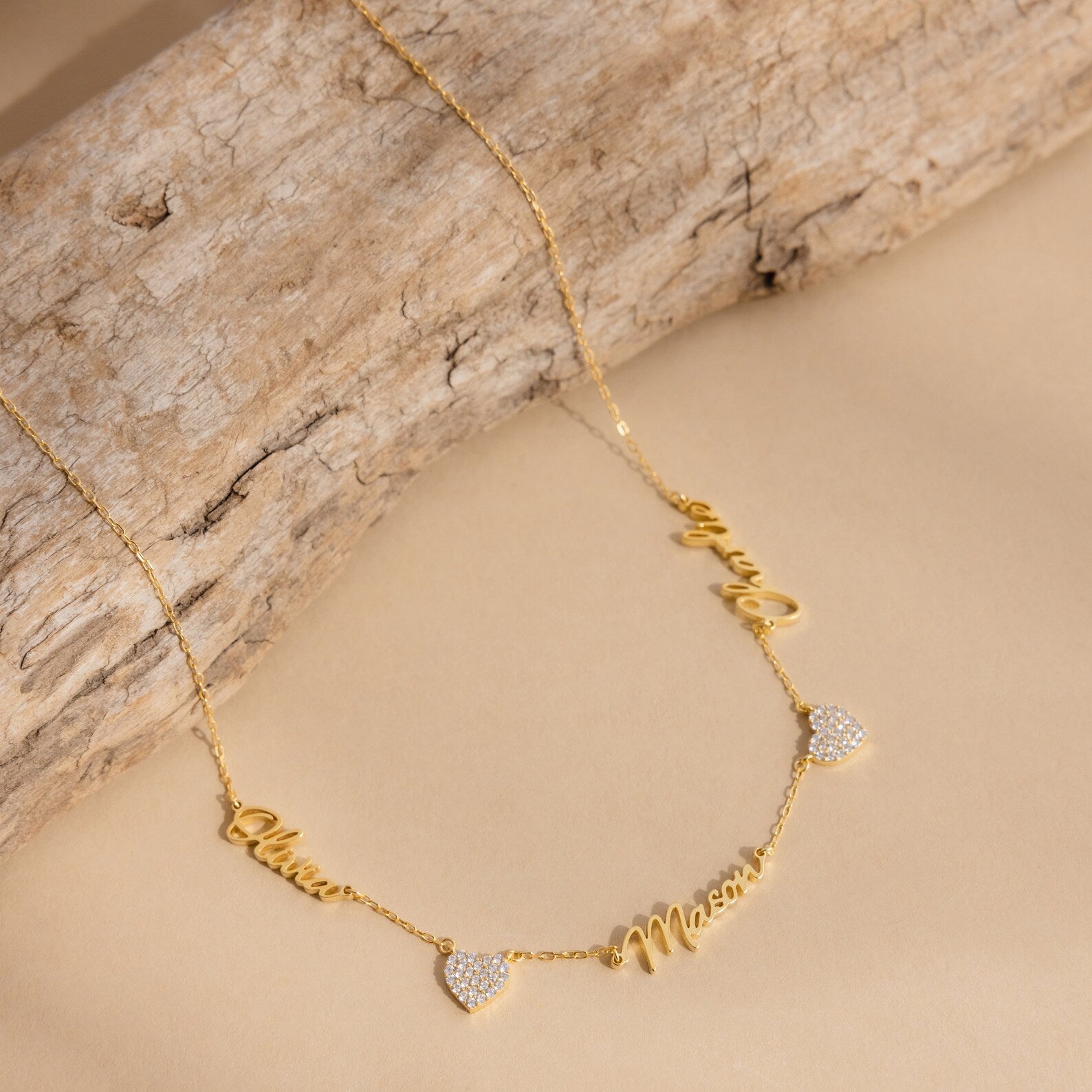 Grace Name Heart Necklace features a gold chain with personalized cursive name and Mom charms, plus two small heart pendants—an elegant custom necklace for any occasion.